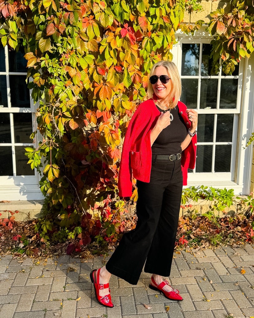 woman wearing all black outfit with red cardigan and shoes.