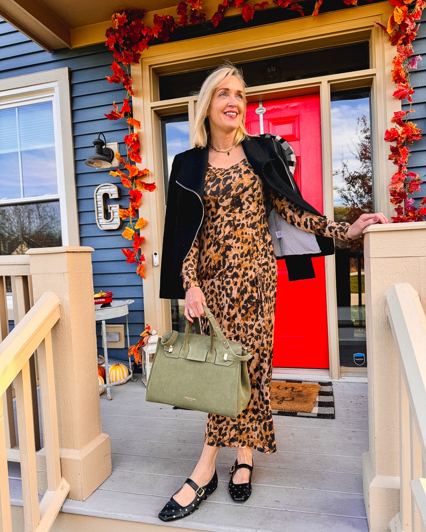 Dressy Thanksgiving outfit with woman wearing leopard print dress and black moto jacket.