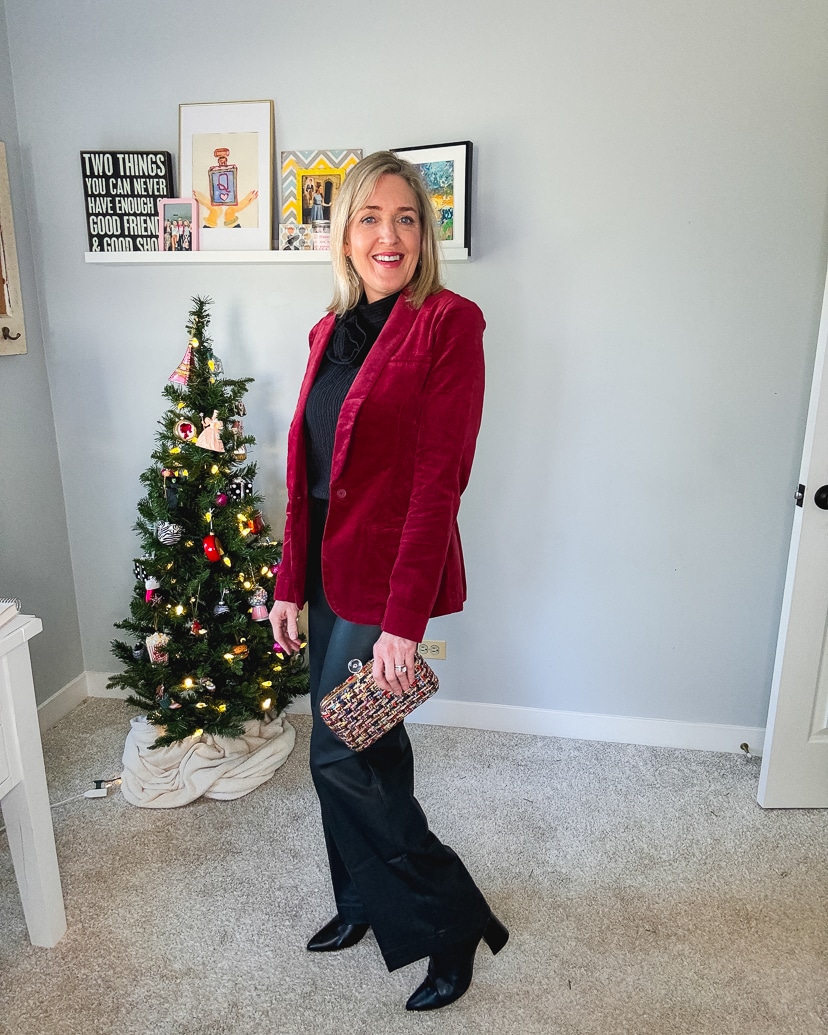 woman wearing a holiday outfit appropriate for the office. Burgundy velvet blazer, black pants and boots.