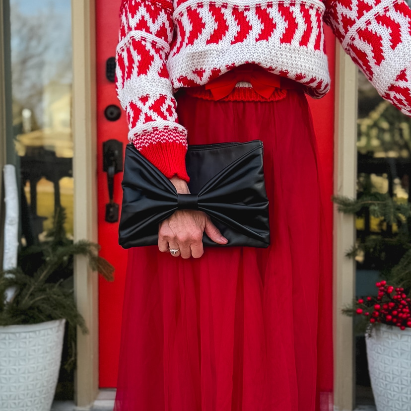 woman wearing a warm and festive holiday outfit with black bow clutch