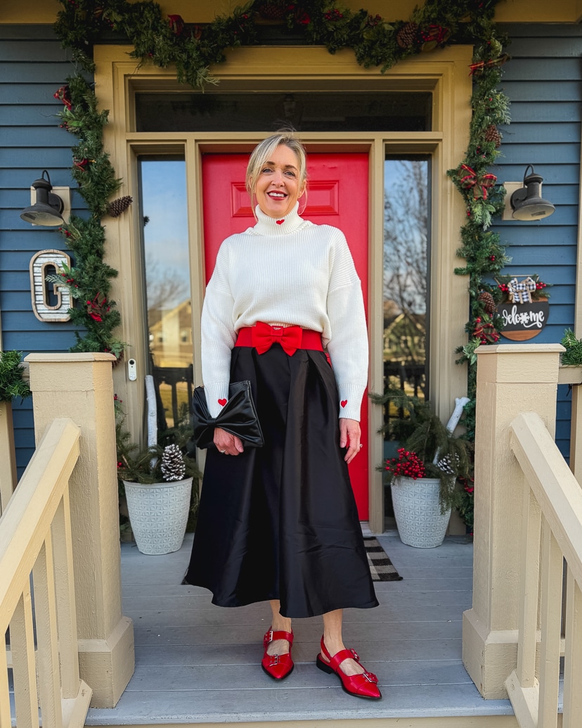 woman wearing a warm and festive black and white christmas outfit with red accessories. 